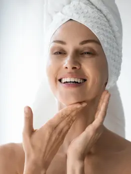 After receiving treatment for an even skin tone, she sparkles & a white towel draped over her head.