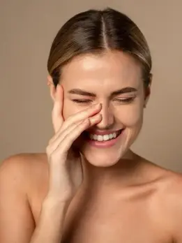 Woman's face shows the results of a pigmentation therapy, she softly touches her face while smiling.