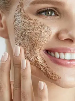 A brown-colored woman is executing a facial mask and grinning. eliminates the presence of dead cells