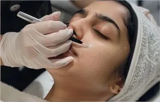 A patient lies down, closes her eyes, & the doctor injects her face to get a beautiful skin texture.