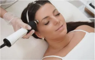 A woman getting a face hair removal treatment using a machine that improves the look of her skin. 