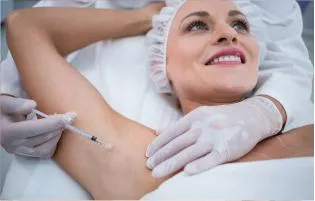 A smiling patient receives therapy for her underarms and the doctor injects her to enhance her skin.