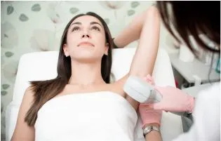 A doctor removes underarm hair for a patient while she is lying down and relaxing her treatment.