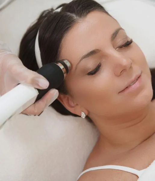 A woman getting a face hair removal treatment using a machine that improves the look of her skin.