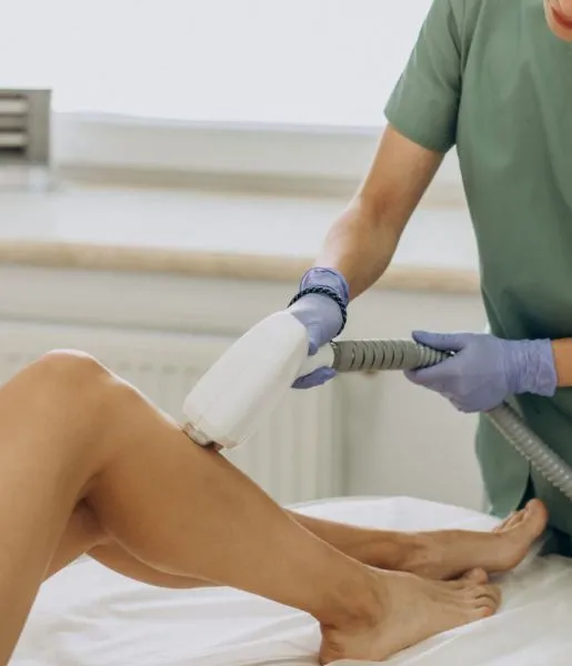 A woman gets laser hair removal on her legs, and a dermatologist is using a laser tool to treat her.