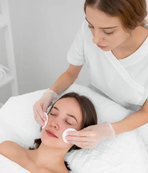 A dermatologist massages a woman's skin following a procedure to remove pimples from her face.