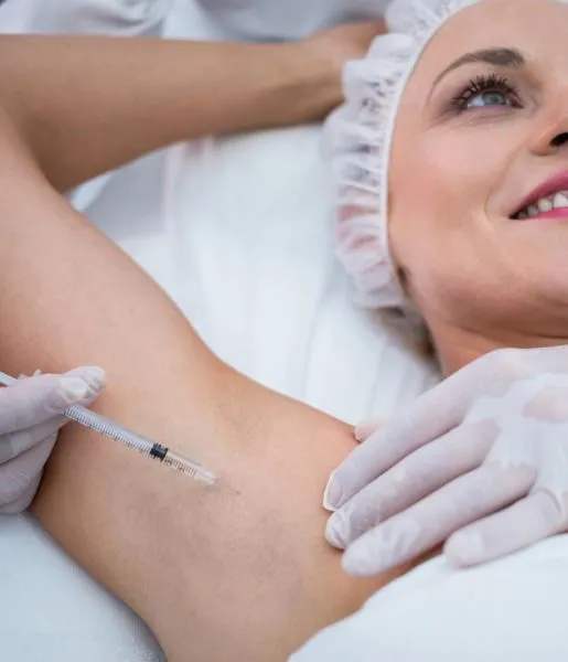 A woman getting an injection for underarm pigmentation from a skin care specialist in a hospital.