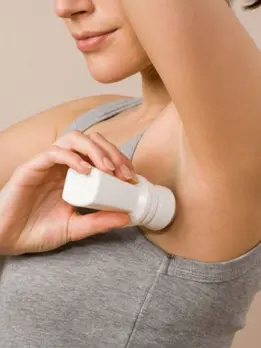 A woman wears a gray dress& applies lotion to her underarm, which helps relieve bacterial body odor.