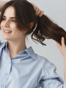 A joyful woman holding her hair with charm got a time-saving hair care treatment for hair styling