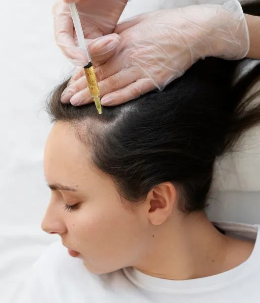 Doctor is injecting  woman's head while she is getting hair transplant surgery to improve her hair.