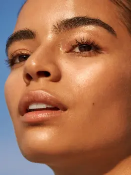 Captured against a bright blue sky is a woman with an outstanding and uniform skin  shade.