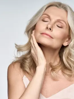 After receiving wrinkle-free treatment, an elderly woman felt overwhelmed & keep her hands on face